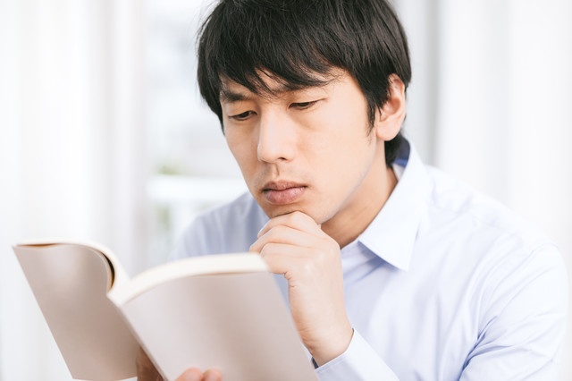 本を読んで考える男性の画像